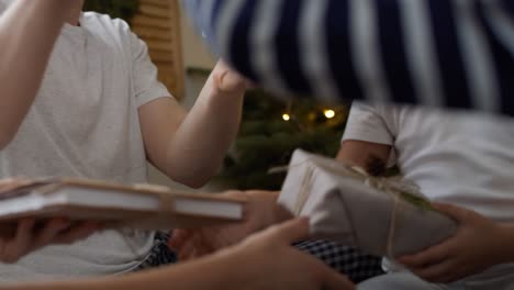 family sharing the christmas presents in bed