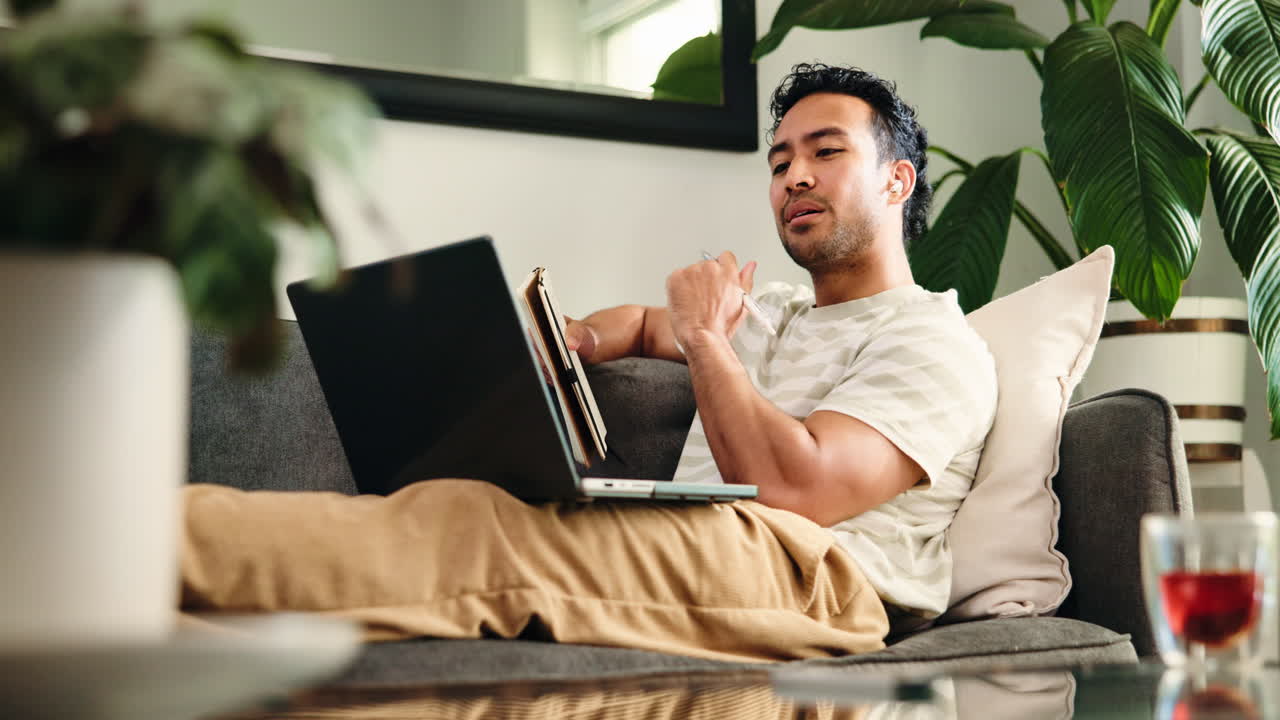 Focused Man Using Laptop and Stylus While Relaxing on Couch