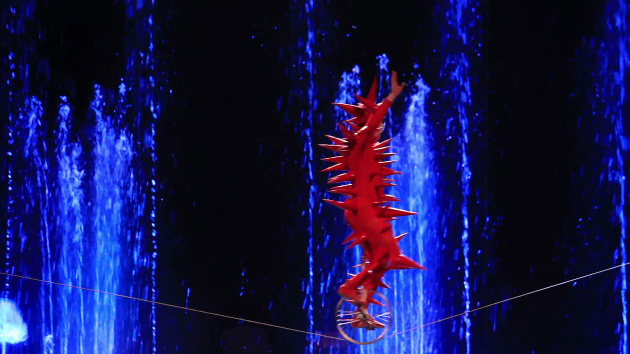 художник едет на одноколесном велосипеде в аквамаринском цирке