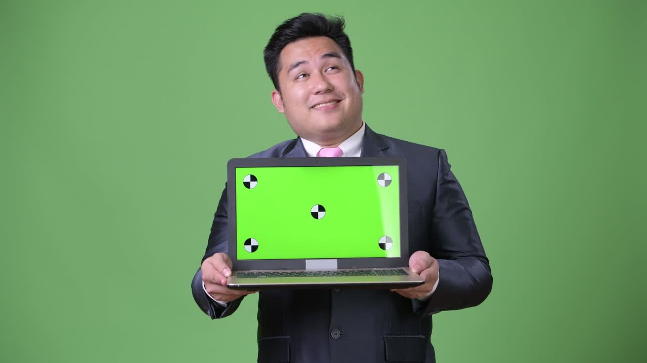 초록색 배경에 젊은 잘생긴 과체중 아시아 사업가