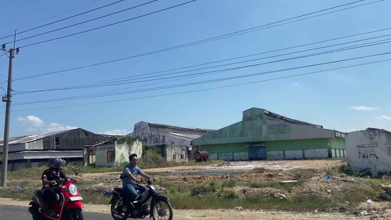 Edifícios Industriais Abandonados e Motocicletas Passando Sob Céu Azul