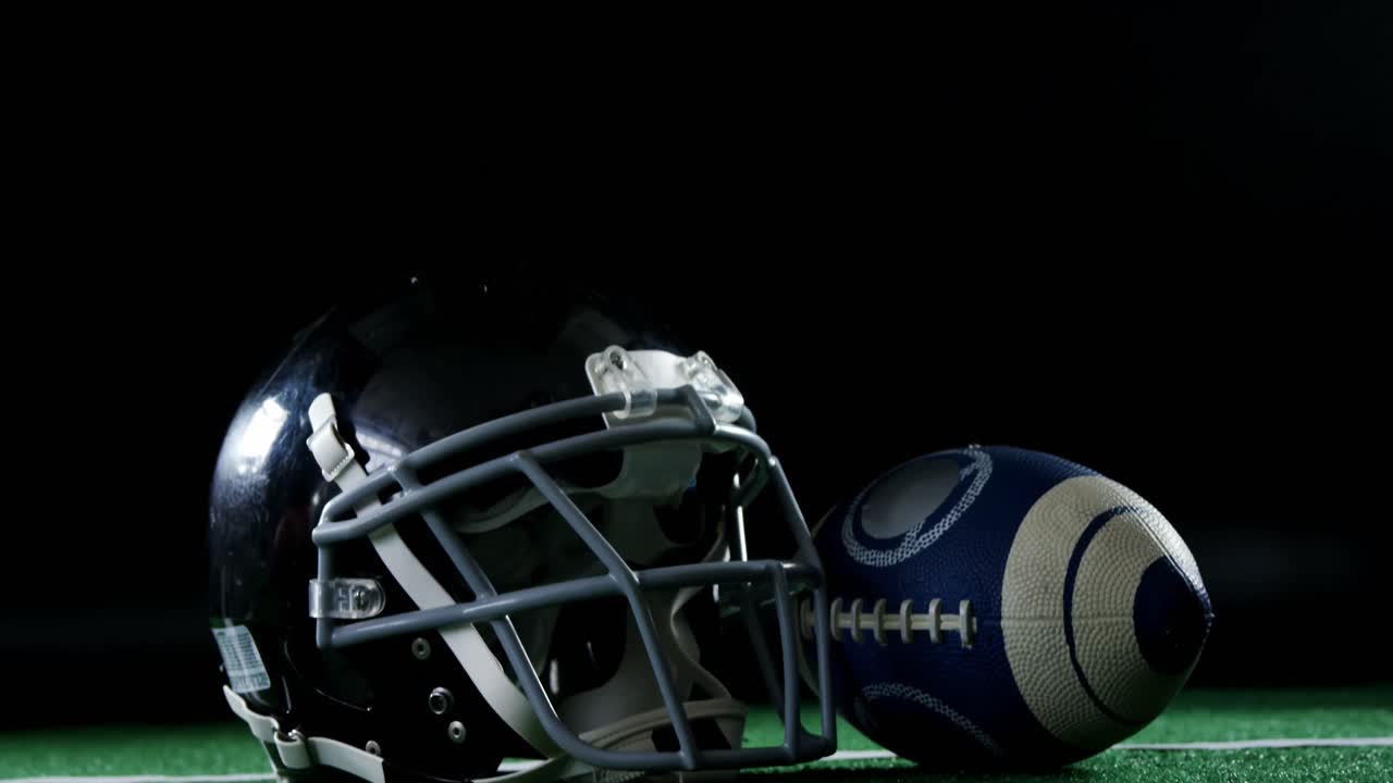 Pallone da football americano e casco su erba sintetica 4k