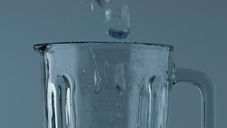 Ice-cubes-falling-blender-container-closeup.-Iced-pieces-filling-grinder-cup.