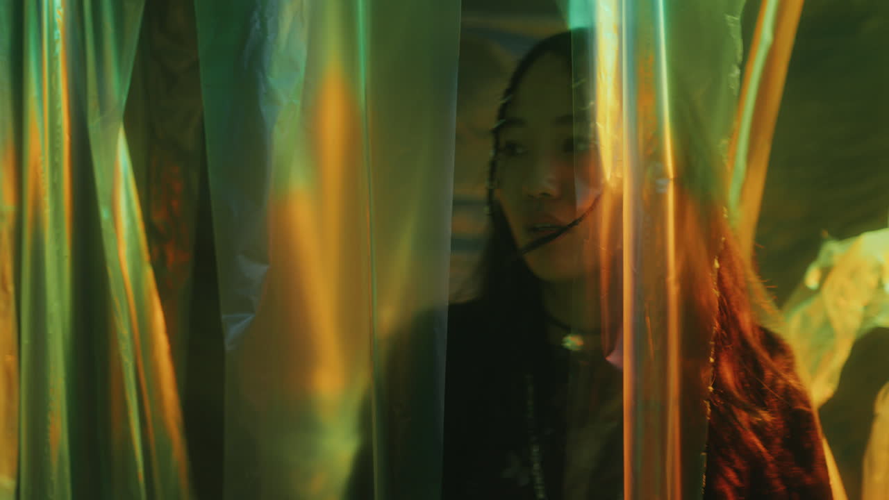 Pretty Asian Woman Walking through Cellophane Curtains in Neon Light