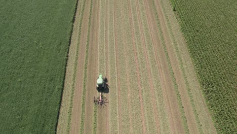 en un campo agrícola en el suroeste de wisconsin, un agricultor rastrilla el heno con un rastrillo giratorio