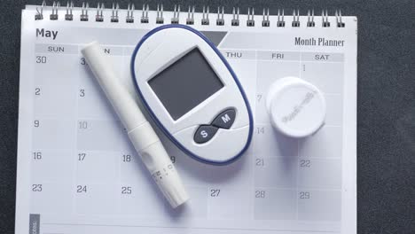 Diabetic-measurement-tools-and-calendar-on-table-,