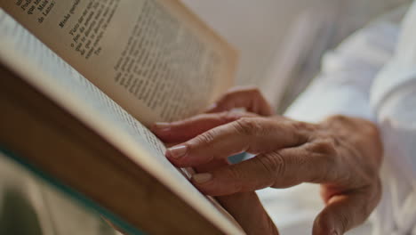 Closeup hands touching book pages running lines. Elderly woman reading novel
