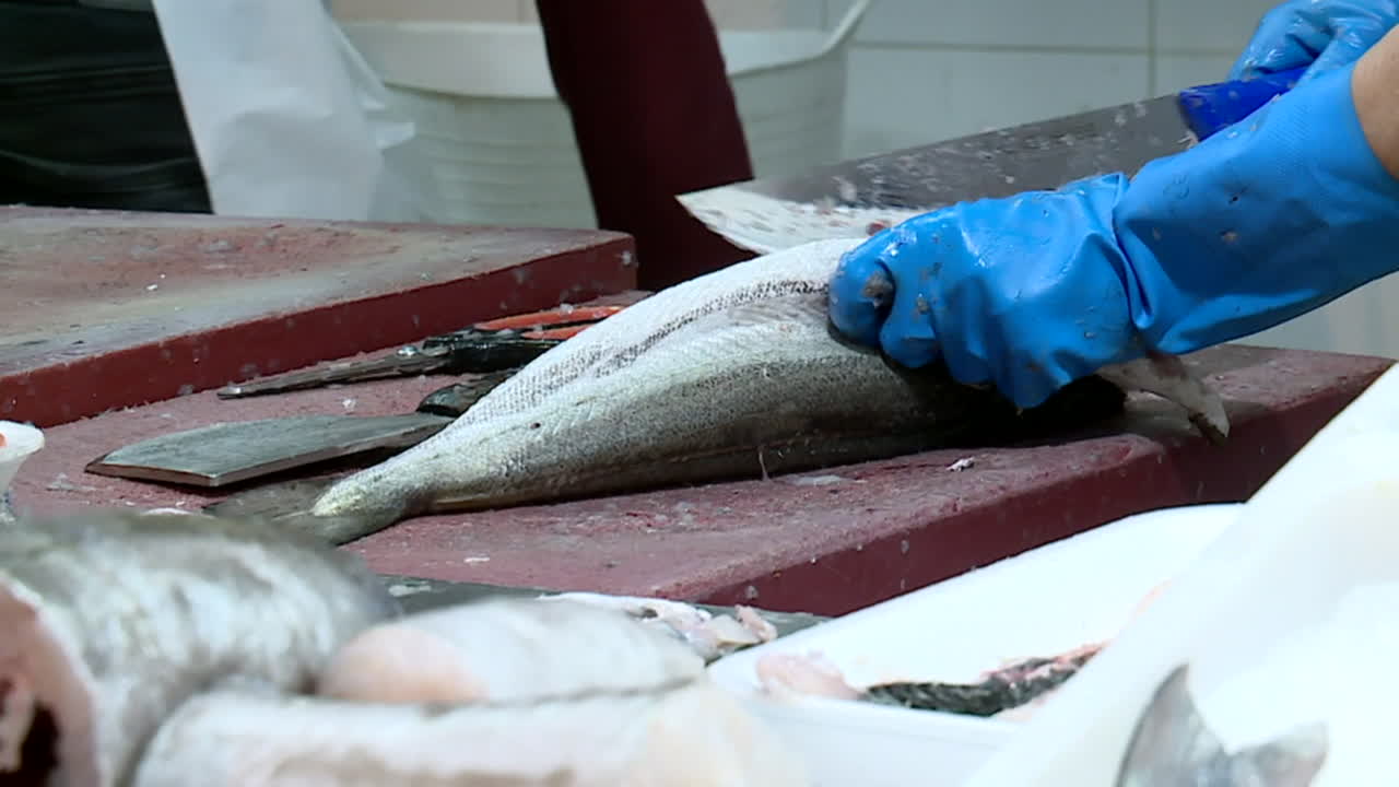 Fishmonger at a market preparing fish