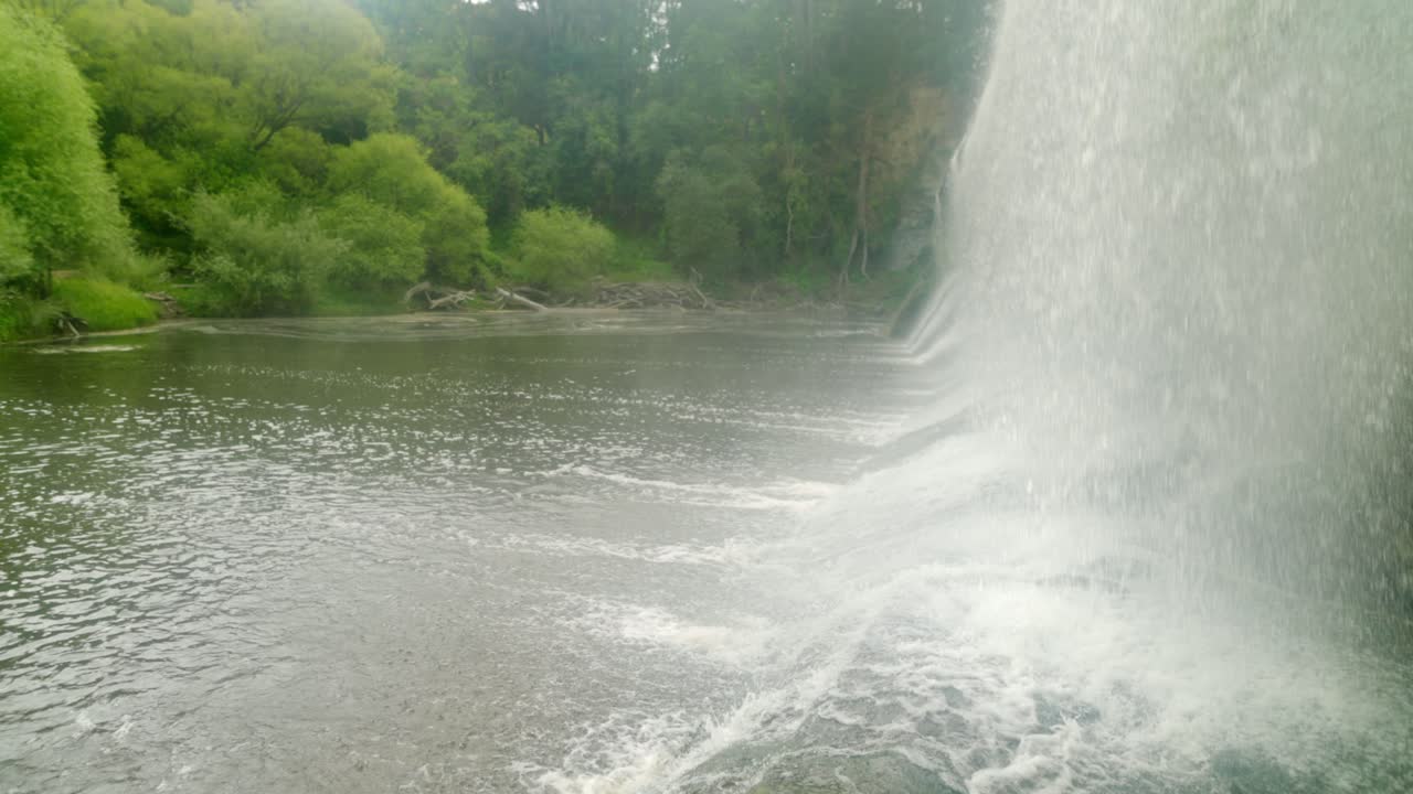 물이 바닥에 충돌할 때 물을 표시하는 폭포 바닥에서 찍은 패닝 샷