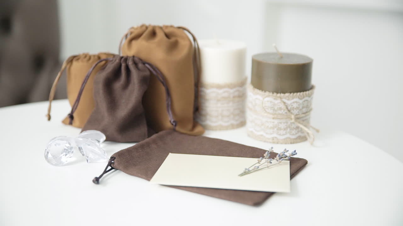 아름다운 여성 손이 촛불이 있는 밝은 흰색 테이블에 결혼식이나 휴가 초대장을 쓰고 있습니다.