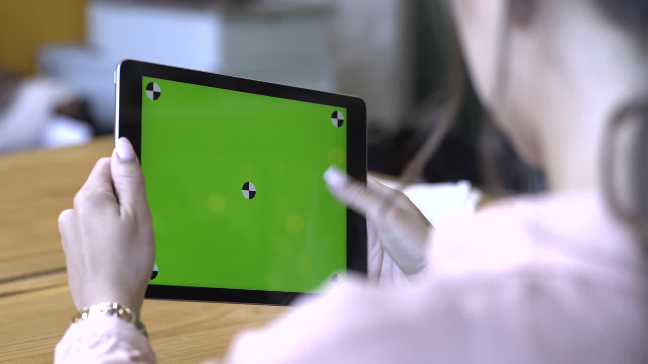 카페 에서 녹색 스크린 을 가진 태블릿 을 들고 있는 여자