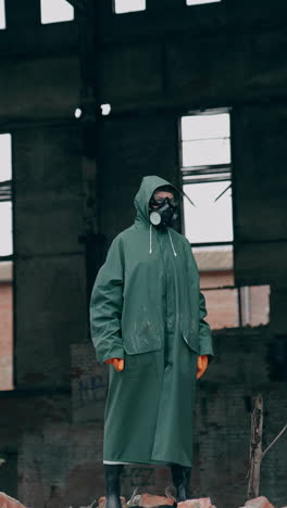 ecologist in safety suit on ruined building background. person in gas mask and protective clothes stands in dangerous place after chemical attack. vertical video