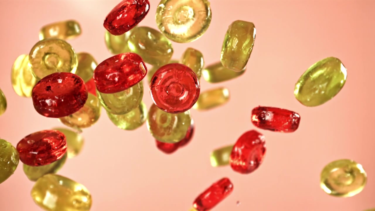Caramelle vivaci rosse e gialle che cadono e galleggiano al rallentatore