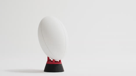 pelota de rugby blanca en patear tee en fondo blanco con espacio de copia, cámara lenta