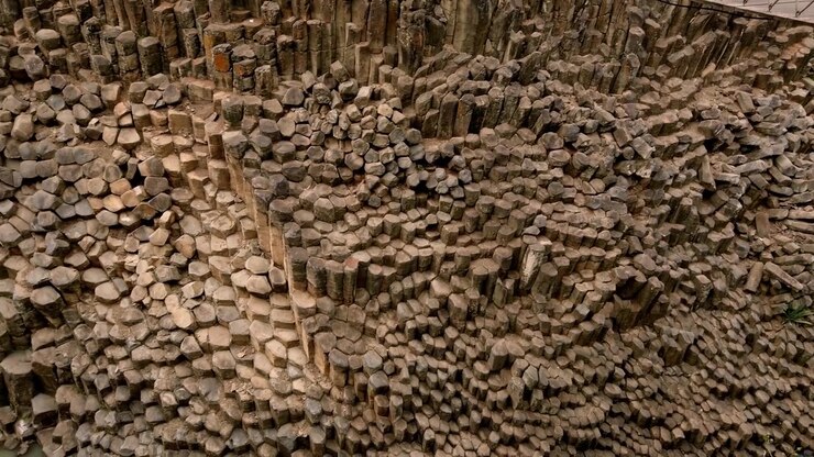 Nærbillede af massive basaltklippeformationer og geometriske vulkanske søjler inde i et naturligt canyonlandskab i Mexico om dagen.