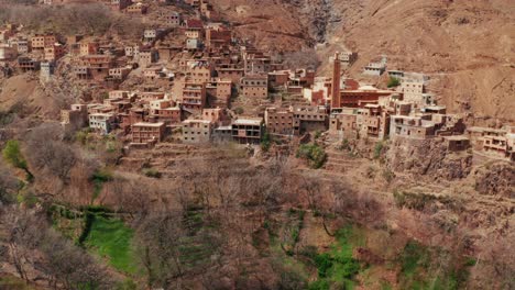aerial drone view of a remote rural moroccan village located on the high atlas mountains in morocco.camera moving backward unveiling the landscape.