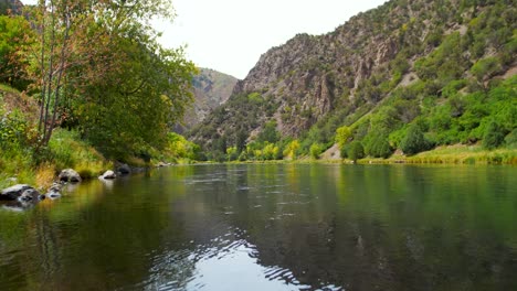 crystal-clear, emerald-like water flows through black canyon of the gunnison national park, colorado. surrounded by lush green trees, gentle waves ripple from a soft breeze, rocky landscapes.