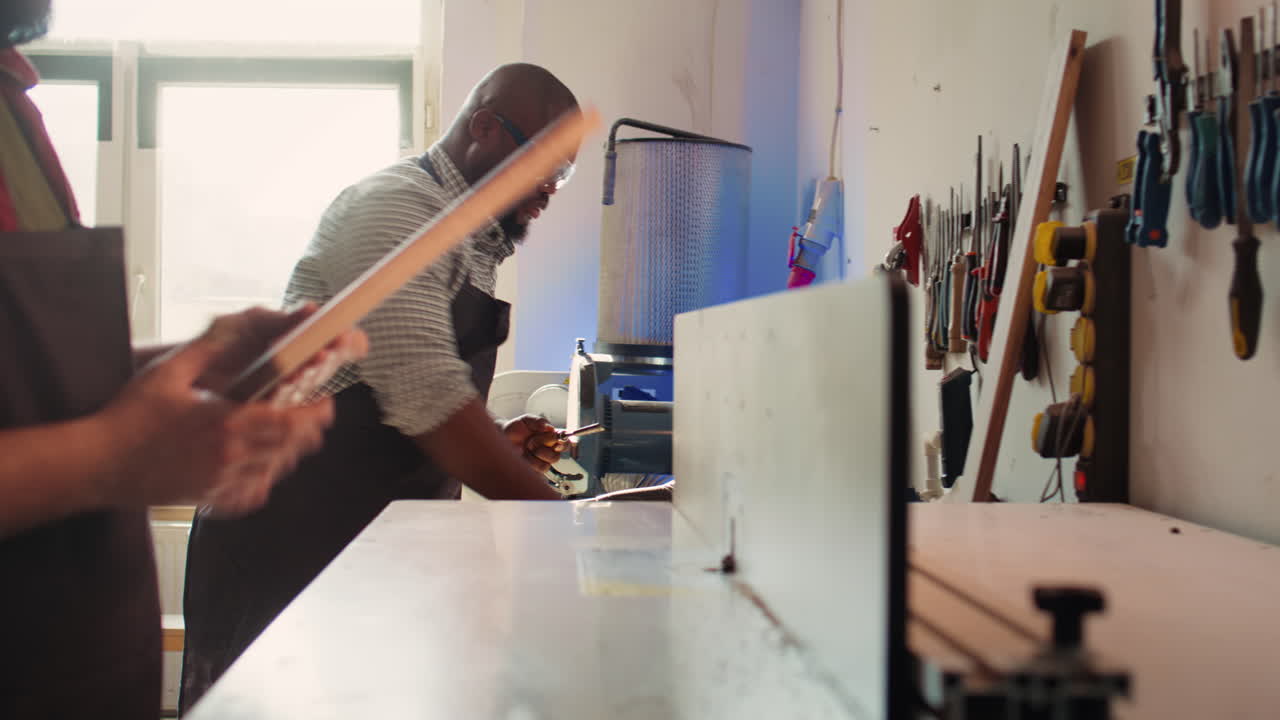 Manufacturer and apprentice performing tasks on wood shaper
