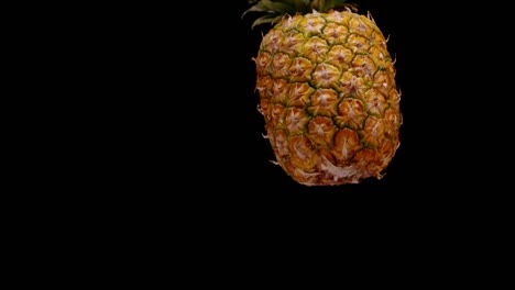 piña entera cayendo aislada en fondo negro, súper lenta