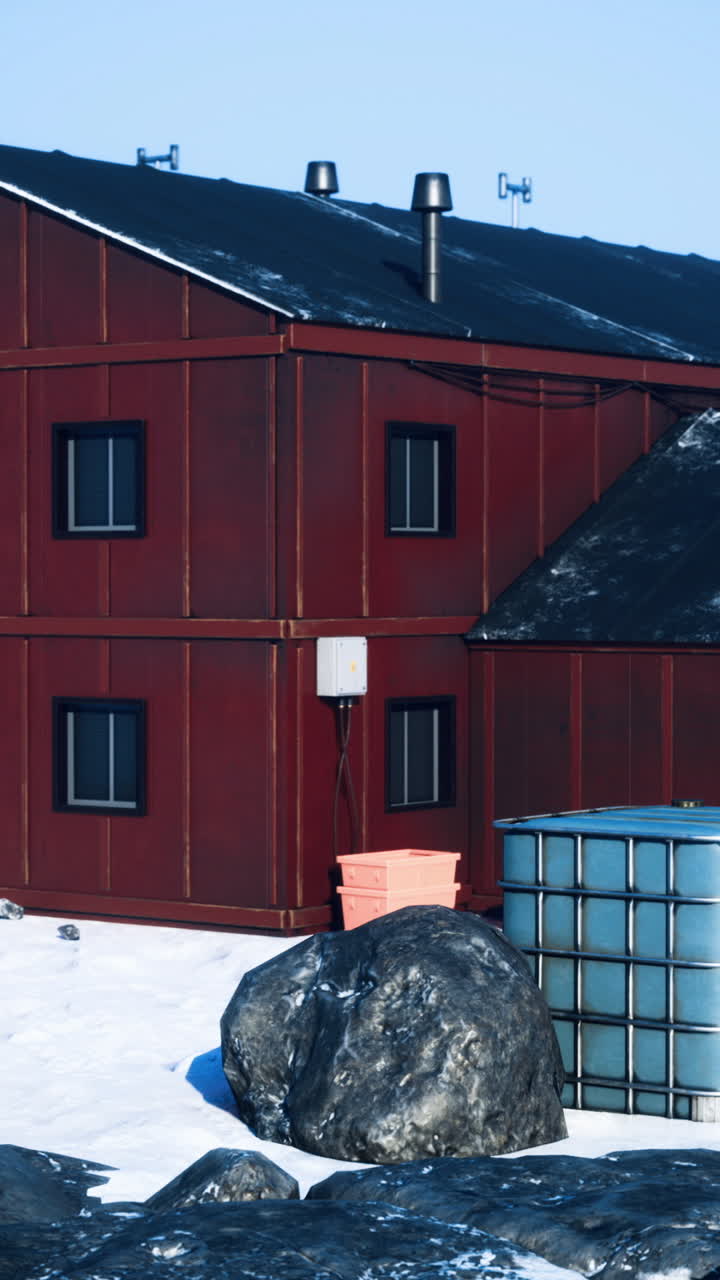 Snow covered red buildings near rocky landscape in a cold icy environment