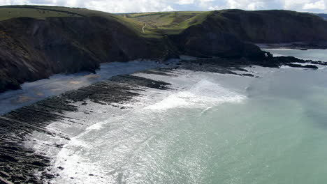 Toma-Aérea-De-Las-Olas-En-El-Mar-Y-Las-Rocas-En-La-Playa-Costera-De-Spekes-Mill-En-Devon