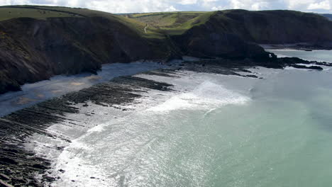 aerial shot of the waves in the sea and the rocks at spekes mill coastal beach in devon