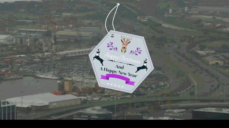 Banner di testo a forma esagonale 'Buon Natale e Felice Anno Nuovo' su vista aerea di paesaggio urbano.