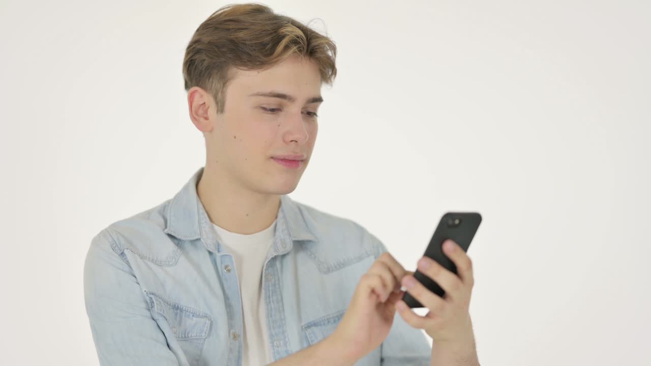 젊은 남자가 색 배경에서 스마트폰을 탐색하고 있습니다.