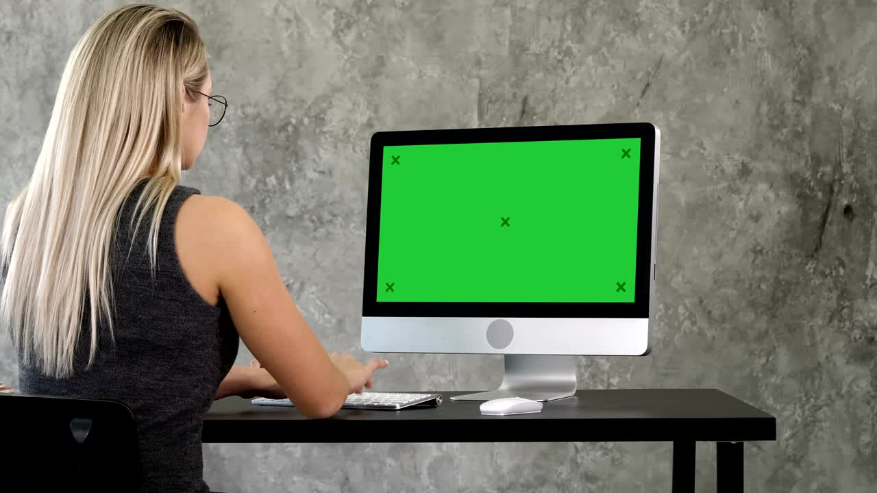 joven mujer de negocios que trabaja en el interior de la oficina en la computadora en el escritorio, escribiendo, mirando la pantalla. pantalla verde muestra de maqueta