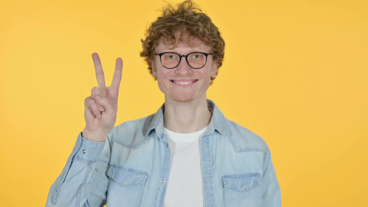 은 머리 젊은이, 노란색 배경의 승리의 표지판