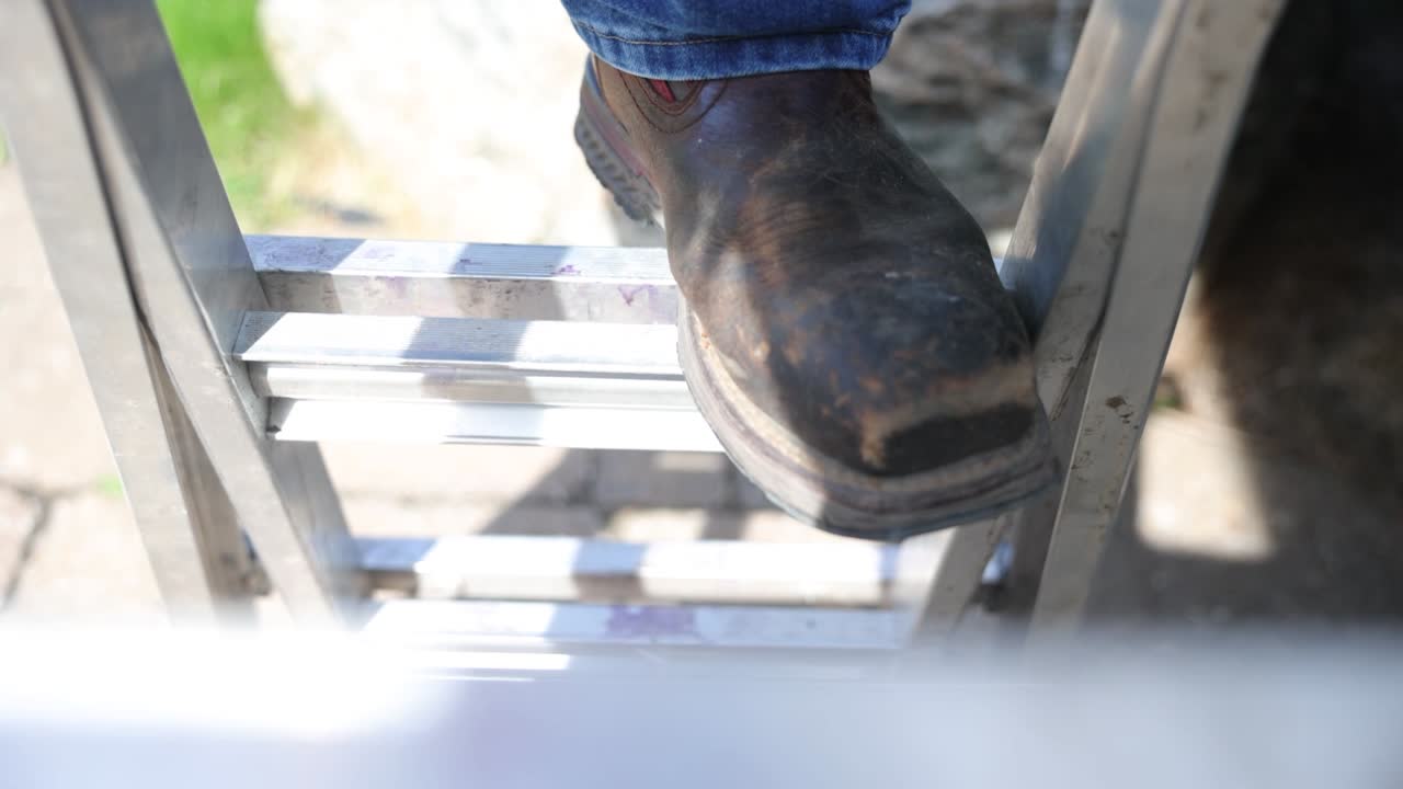 Man climbs a ladder on a job site to repair a roof