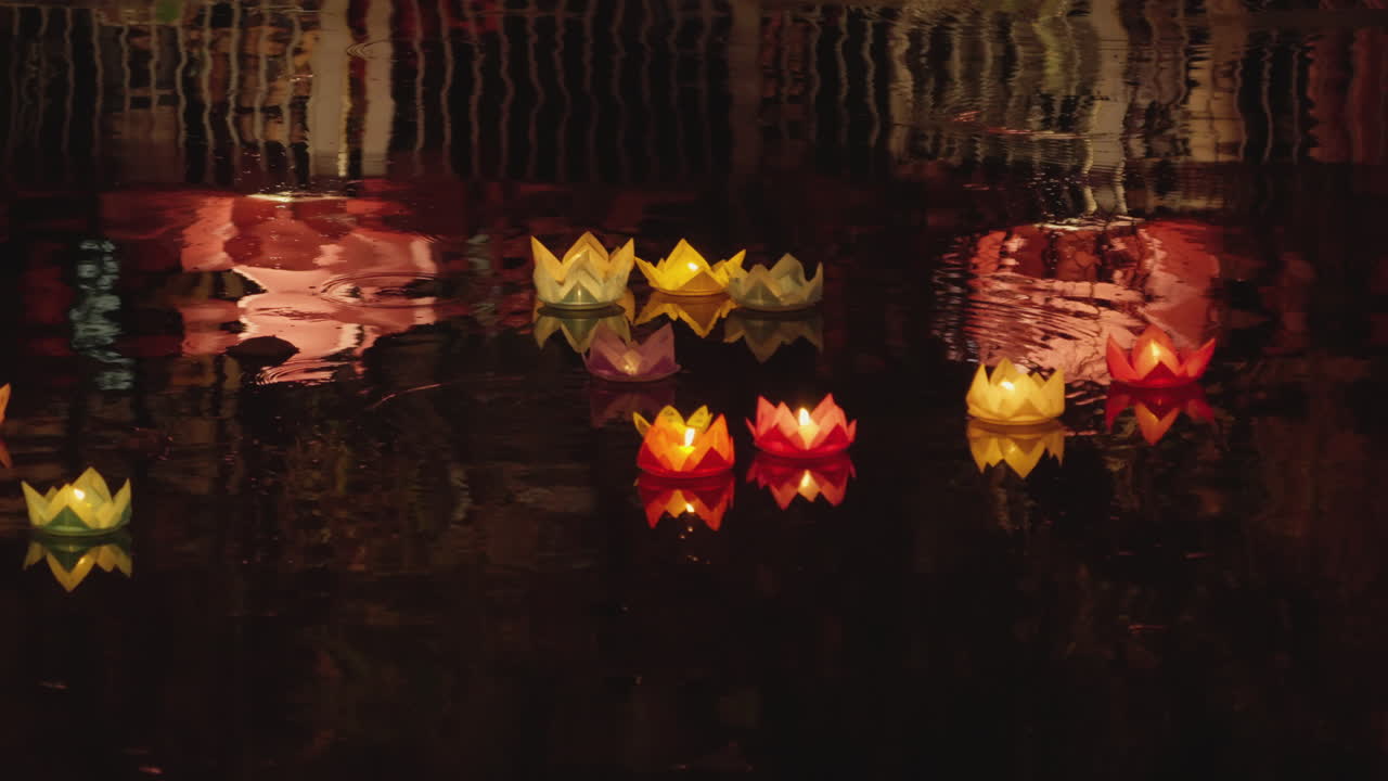 Linterna de papel con forma de flor de loto flotando en el agua del río por la noche para la celebración anual de los festivales budistas de Vesak en el sudeste asiático.