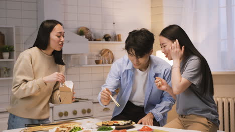 three japanese friends eating ramen and sushi in the kitchen