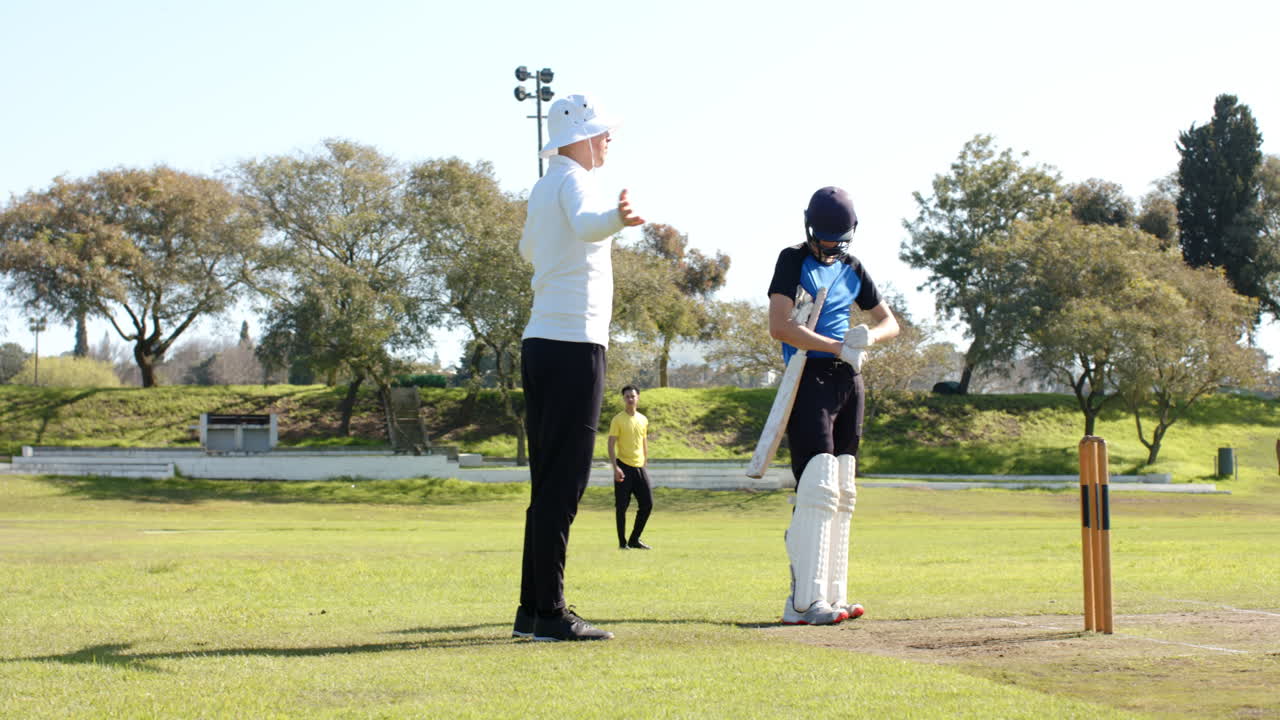 Cricket coach guiding young player on sunny field, sharing techniques