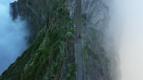 young and fit man is walking alone up the trail to the top of pico do arieiro in madeira