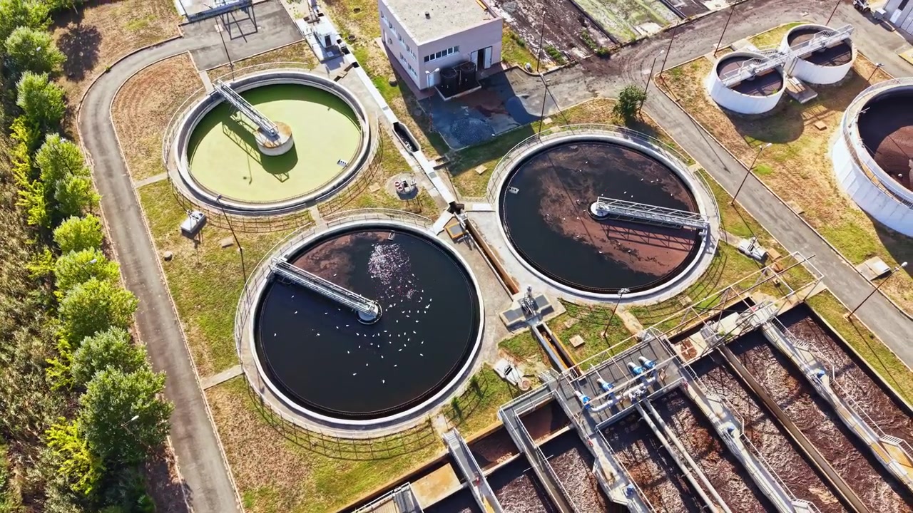 Wastewater treatment facility showing various tanks and equipment in operation during midday hours