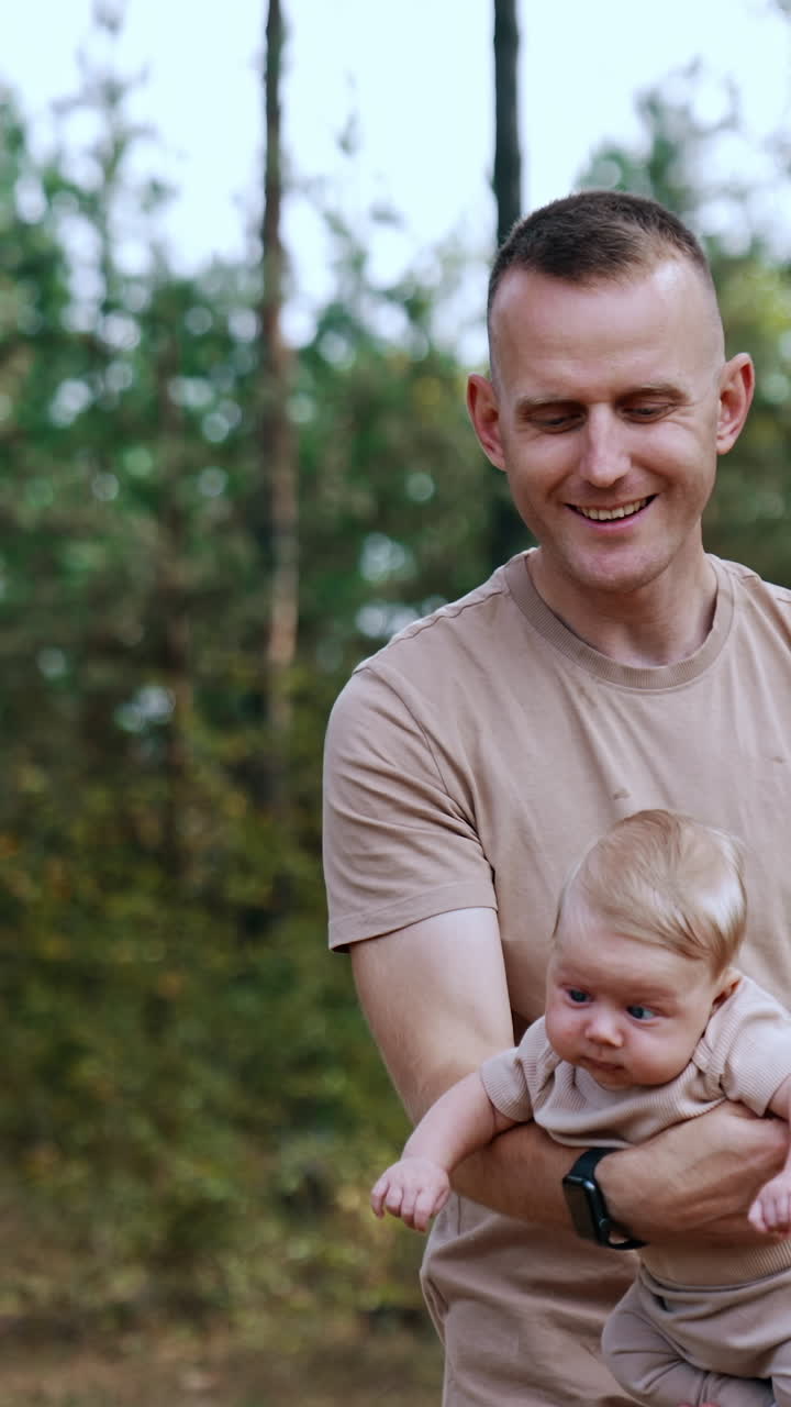 Uomo con una t-shirt beige saluta il suo bambino. Padre felice che passa del tempo con il figlio nella natura. Video verticale