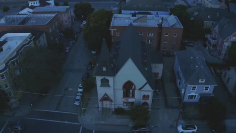 a small church stands dwarfed in the shadows of big business and huge corporations