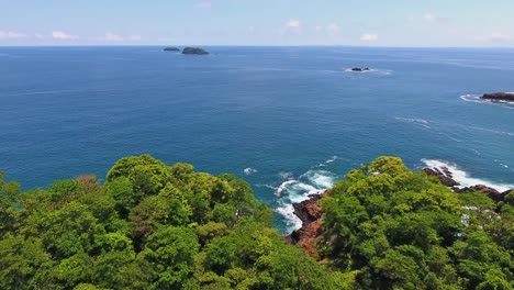 Rollo-Hacia-Adelante-Revela-La-Costa-Rocosa-Con-Olas-De-Agua-Azul-Rompiendo