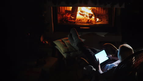 a woman is resting by the fireplace using a tablet view from above