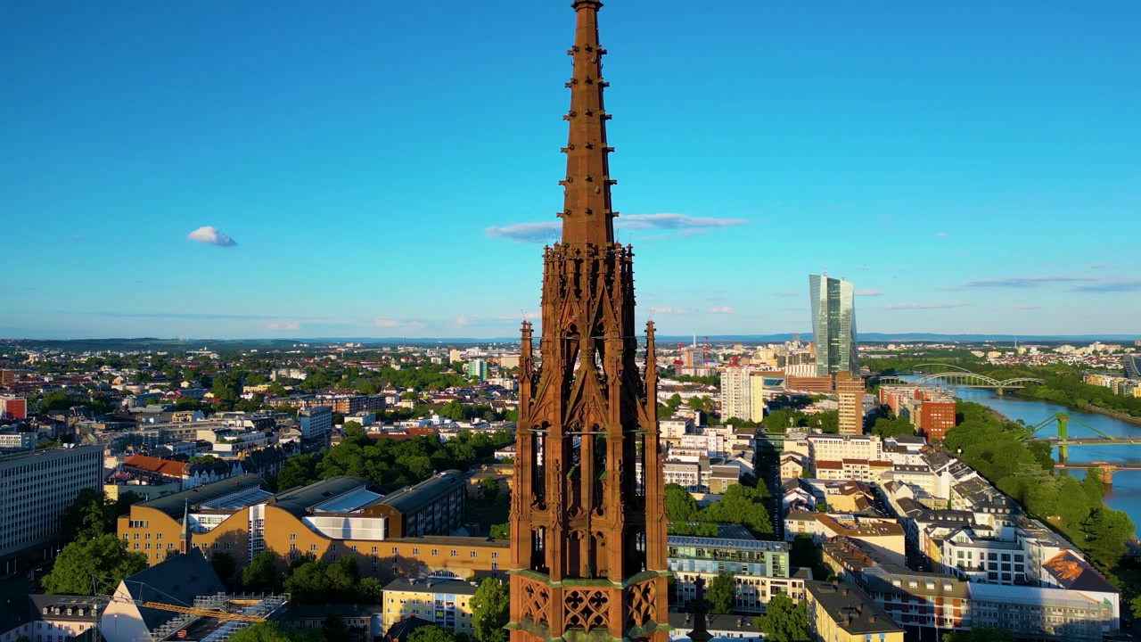 4K Drone Video of the Spire of the Gothic-Style Kaiserdom St. Bartholomäus Cathedral with the Modern European Central Bank Building in the Distance on the Main River in Downtown Frankfurt, Germany