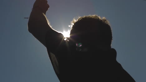 dj in the sunshine. outdoors a musical producer plays electronic music and waits for the drop to sound. sun rays fall from the sky creating his silhouette
