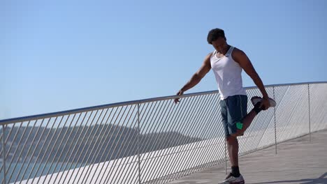 happy athletic man stretching leg at sunny day