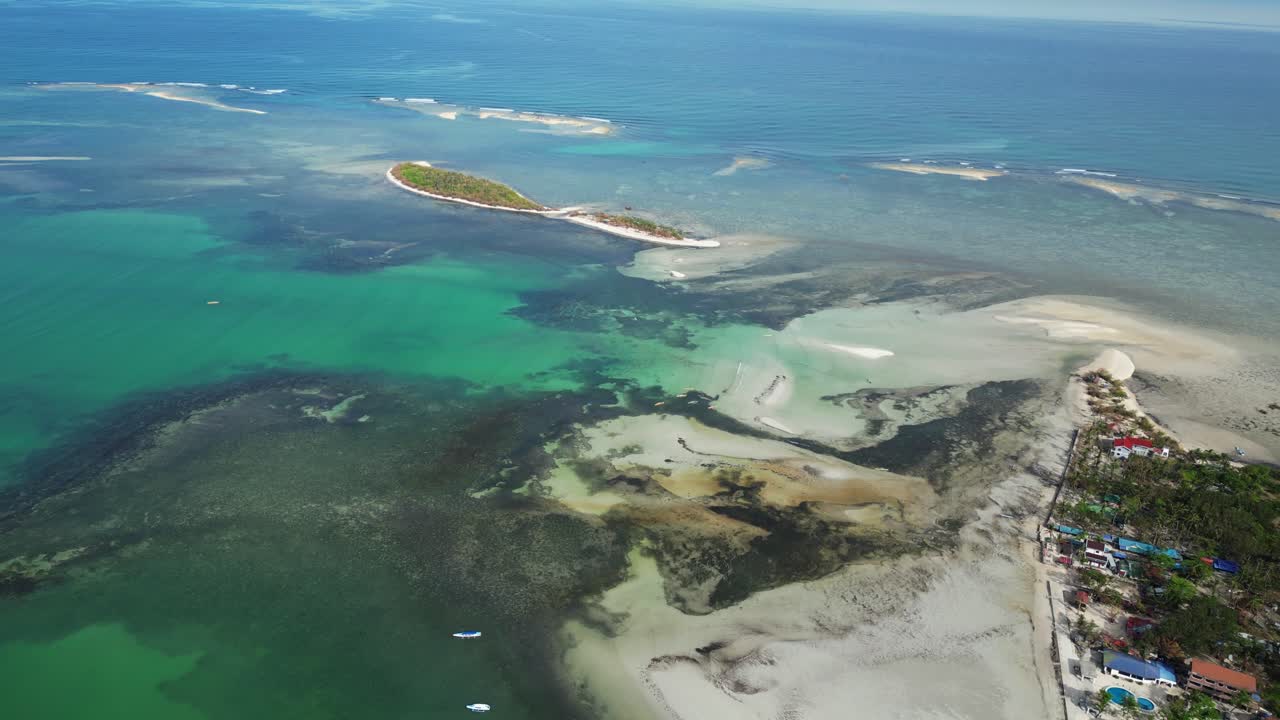 Aérea ampla de paisagem marinha natural destacando ilha coberta de palmeiras, praias de areia branca e água cristalina.