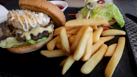 una deliciosa hamburguesa y papas fritas servidas en un hermoso plato de pizarra negra