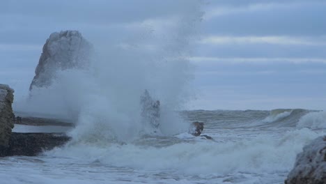 big stormy waves breaking against abandoned seaside fortification building ruins at karosta northern forts in liepaja, slow motion medium shot