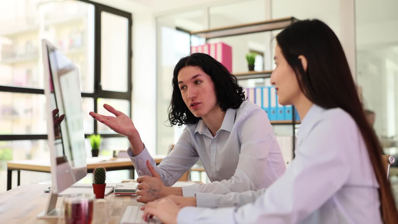 Two colleagues collaborating and discussing work in a modern office
