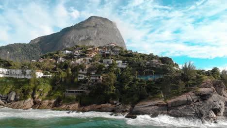 distanciamiento aéreo de las hermosas y pintorescas rocas de los acantilados de la playa de joatinga en río de janeiro con la montaña givea elevándose detrás de ella y las verdes olas del océano rodando