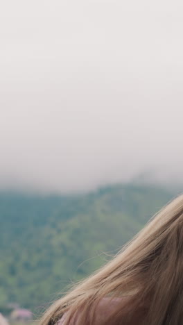 blonde mother strokes little daughter hair locks enjoying together misty mountains view at highland eco resort close backside view slow motion