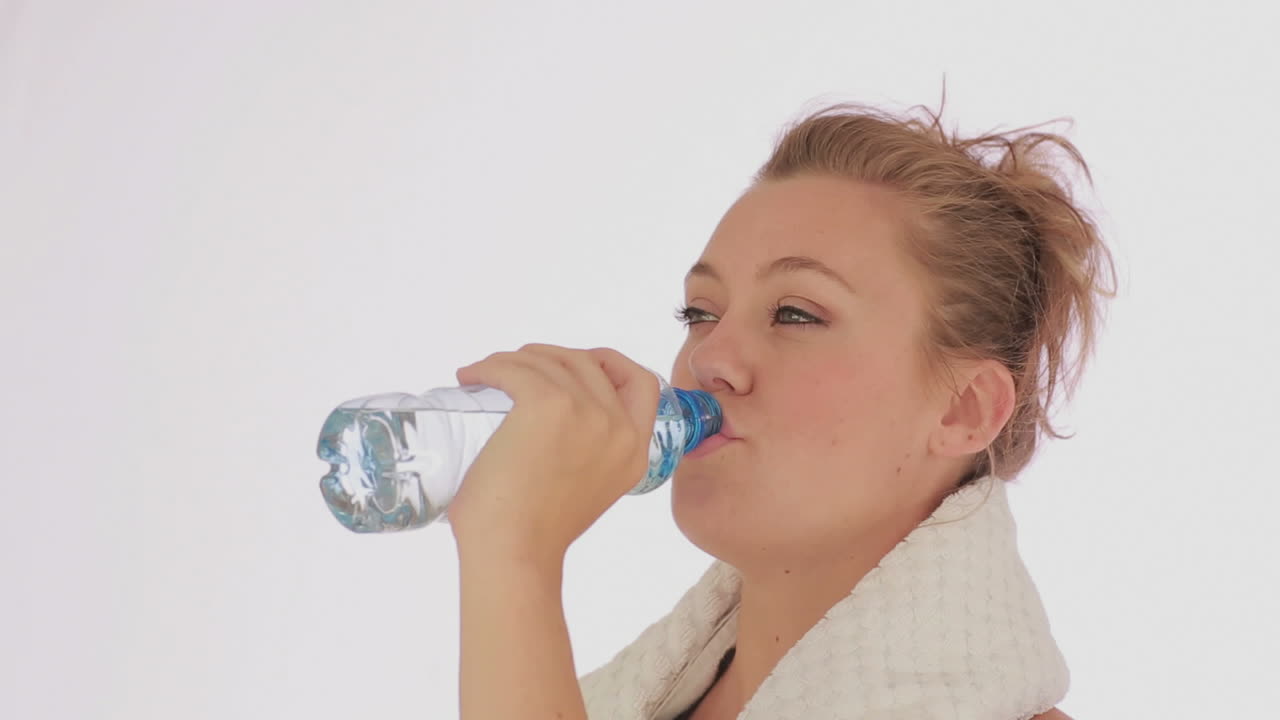 스포츠 를 한 후 병 에 담긴 물 을 마시는 여자